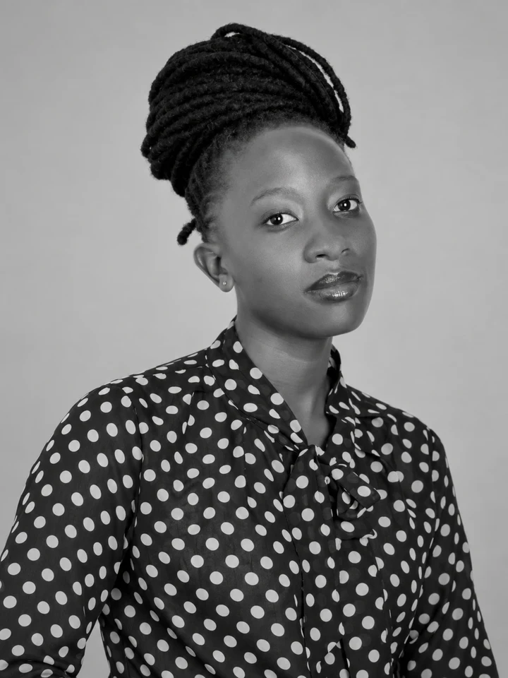 Mazirwe with a braided top-knot in a polka-dot blouse