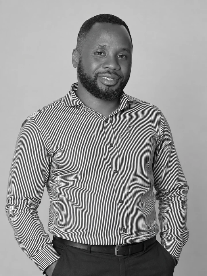 Obed smiling in a striped shirt, framed close