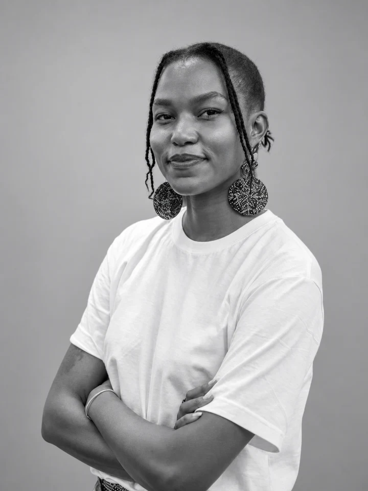 Wandia seated outdoors in a white tee and statement earrings